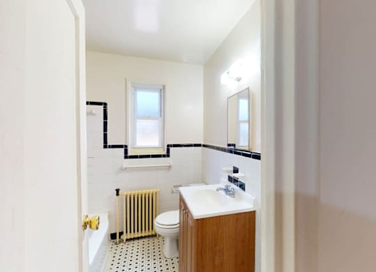 A bathroom with a toilet, sink, and window.