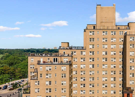 A large tan building with a parking lot in front of it.