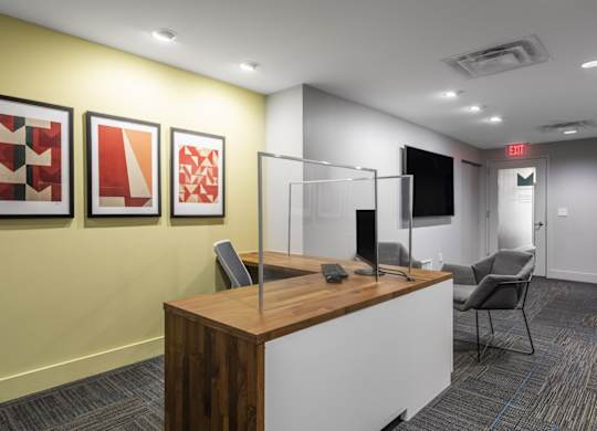 A reception area with a wooden desk and three framed artworks on the wall.