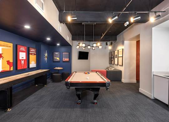 A pool table is in the middle of a room with a blue wall and a TV.