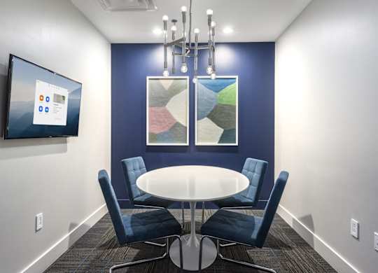 A conference room with a table, chairs, and a screen on the wall.