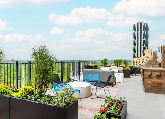 A rooftop patio with a table and chairs overlooking a cityscape.