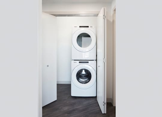 A white washing machine is in a small white room.