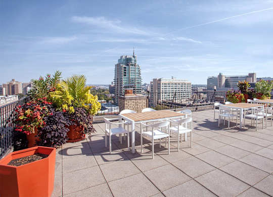 A rooftop patio with a table and chairs overlooking a city skyline.