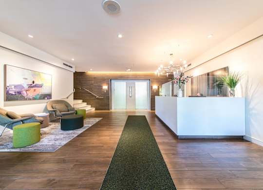 A reception area with a white reception desk and a green carpet.