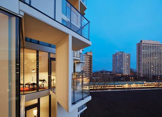 A modern building with a balcony overlooking a cityscape at dusk.