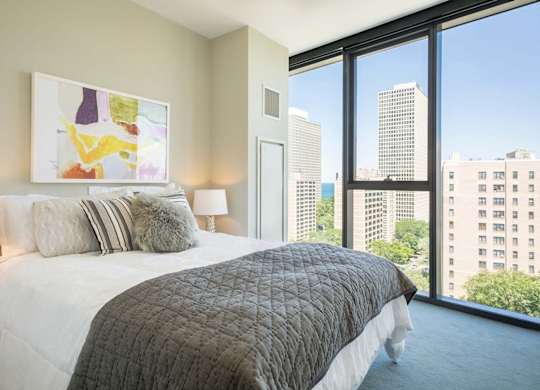 A bedroom with a large bed and a view of the city.