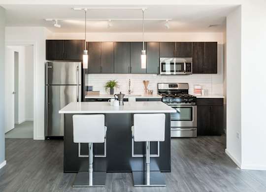 A modern kitchen with a white countertop and black bar stools.