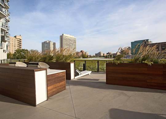 A rooftop patio with wooden furniture and a view of the city.