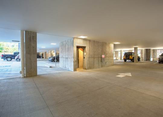 A parking garage with a concrete floor and pillars.