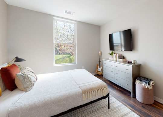 A bedroom with a bed, a dresser, and a window.