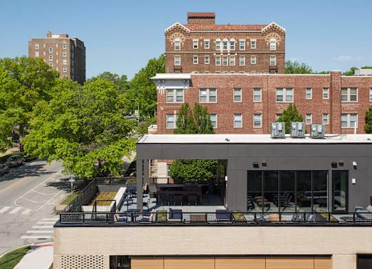 A modern building with a balcony is in front of a red brick building.
