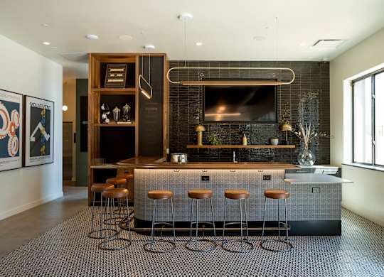 A modern kitchen with a bar area and stools.