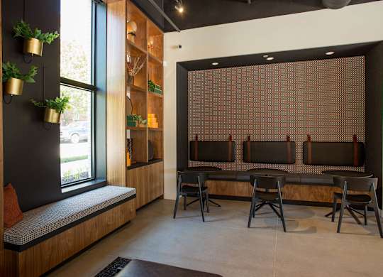A room with a bench, chairs and a window.