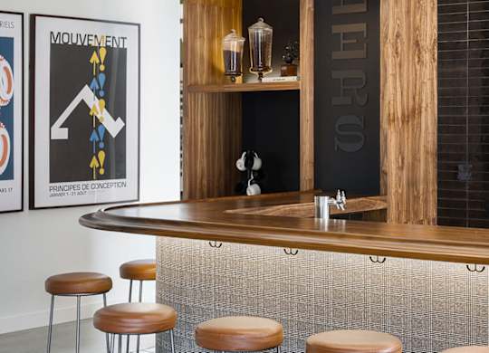 A bar with a wooden shelf and a black and white poster on the wall.