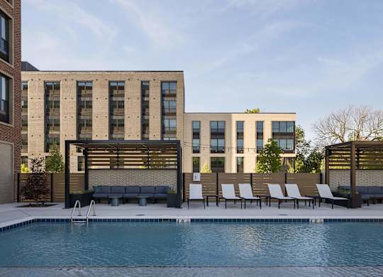 A pool in front of a building with a bench and chairs.