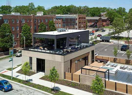 A modern building with a glass entrance sits in front of a parking lot.