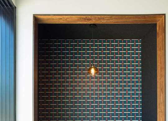 A black and white tiled wall with a wooden frame and a table and bench in front of it.