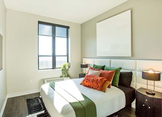 A bedroom with a bed, pillows, and a lamp.