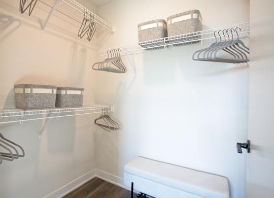A white closet with clothes hanging on hangers.