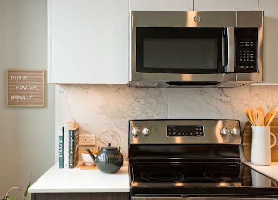 A modern kitchen with a stove, microwave, and a sign that says