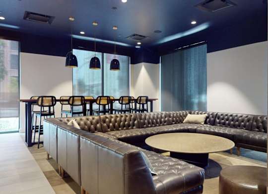 A black and brown leather couch with a round table in front of it.