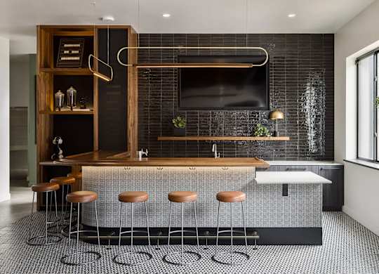 A modern kitchen with a bar area and stools.