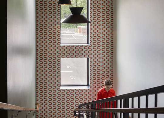 A man in a red shirt is walking down a staircase.