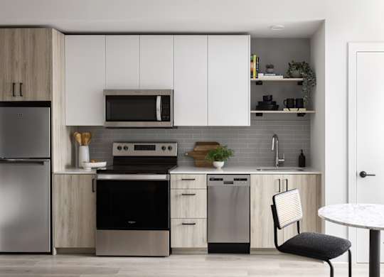 A modern kitchen with a refrigerator, oven, and microwave.