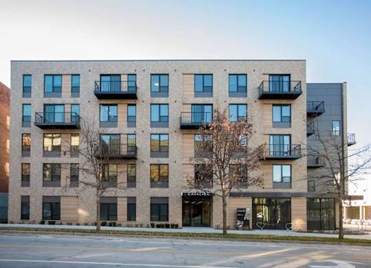 A modern apartment building with balconies and a storefront on the ground floor.
