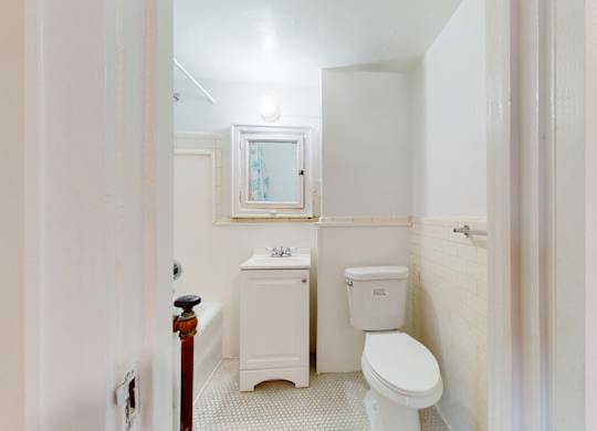 A white toilet sits next to a white sink in a small bathroom.