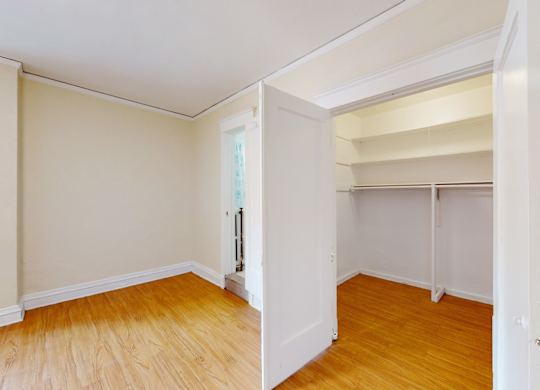A room with a white door and wooden flooring.