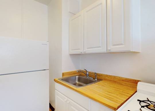 A white refrigerator is in a kitchen with a wooden counter top.