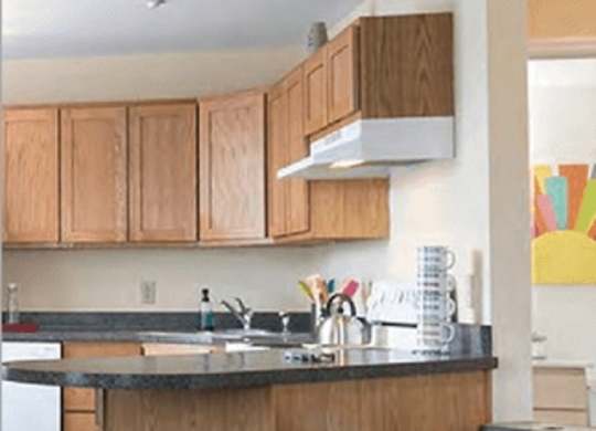 A kitchen with wooden cabinets and a bar stool.