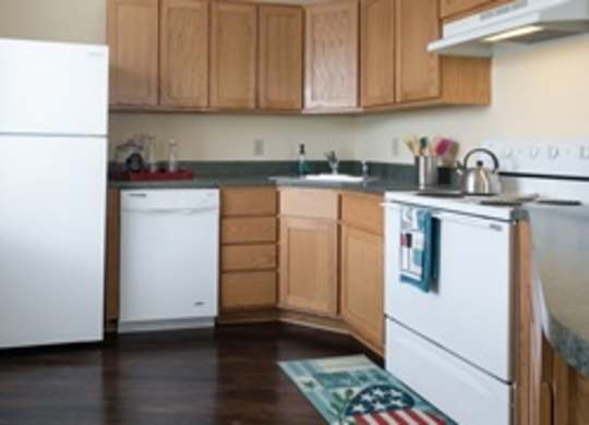 A kitchen with white appliances and wooden cabinets.