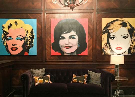Three portraits of women are displayed on a wall above a couch.