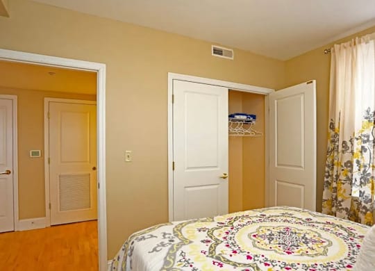 A bedroom with a bed, two closets, and a window.