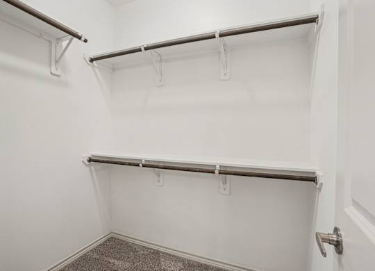 A white closet with two shelves and a carpeted floor.