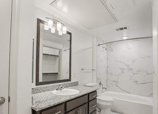 A bathroom with a marble patterned wall and a white toilet.