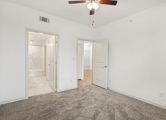 A room with a ceiling fan and carpeted floor.
