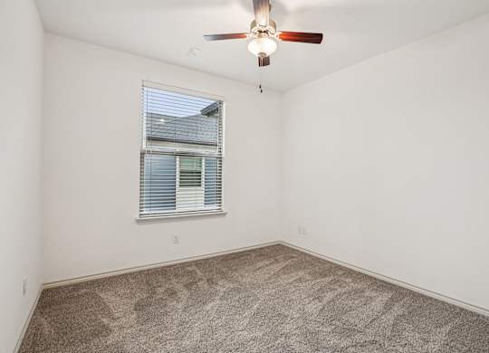 A room with a ceiling fan and a window with blinds.