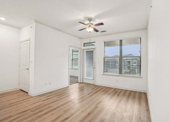 A room with a ceiling fan and wooden flooring.