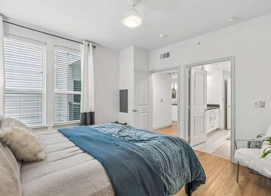 A bedroom with a large bed and a white chair.