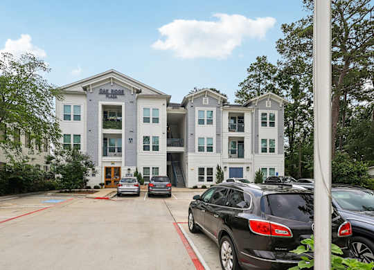A car dealership with a white building and several cars parked in front.