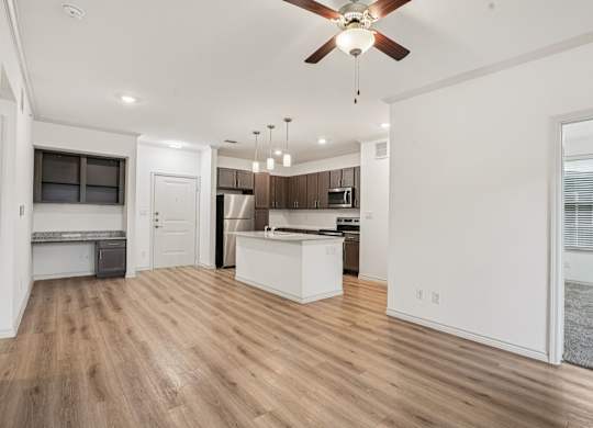 A spacious kitchen and living room with wooden floors and white walls.