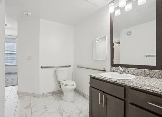 A white toilet in a bathroom with a sink and mirror.