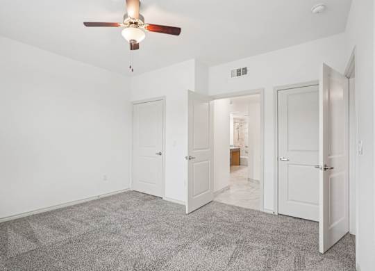 A room with a ceiling fan and carpeted floor.