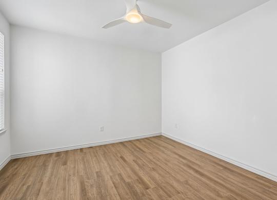 A room with a ceiling fan and wooden flooring.