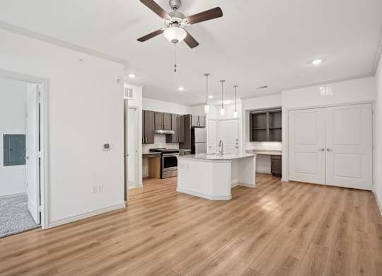 A spacious kitchen with a ceiling fan and wooden flooring.