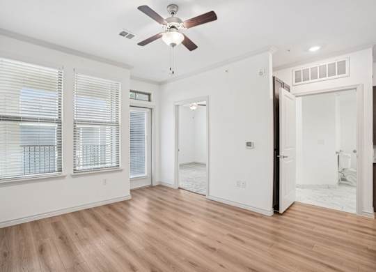 A room with a ceiling fan and wooden flooring.